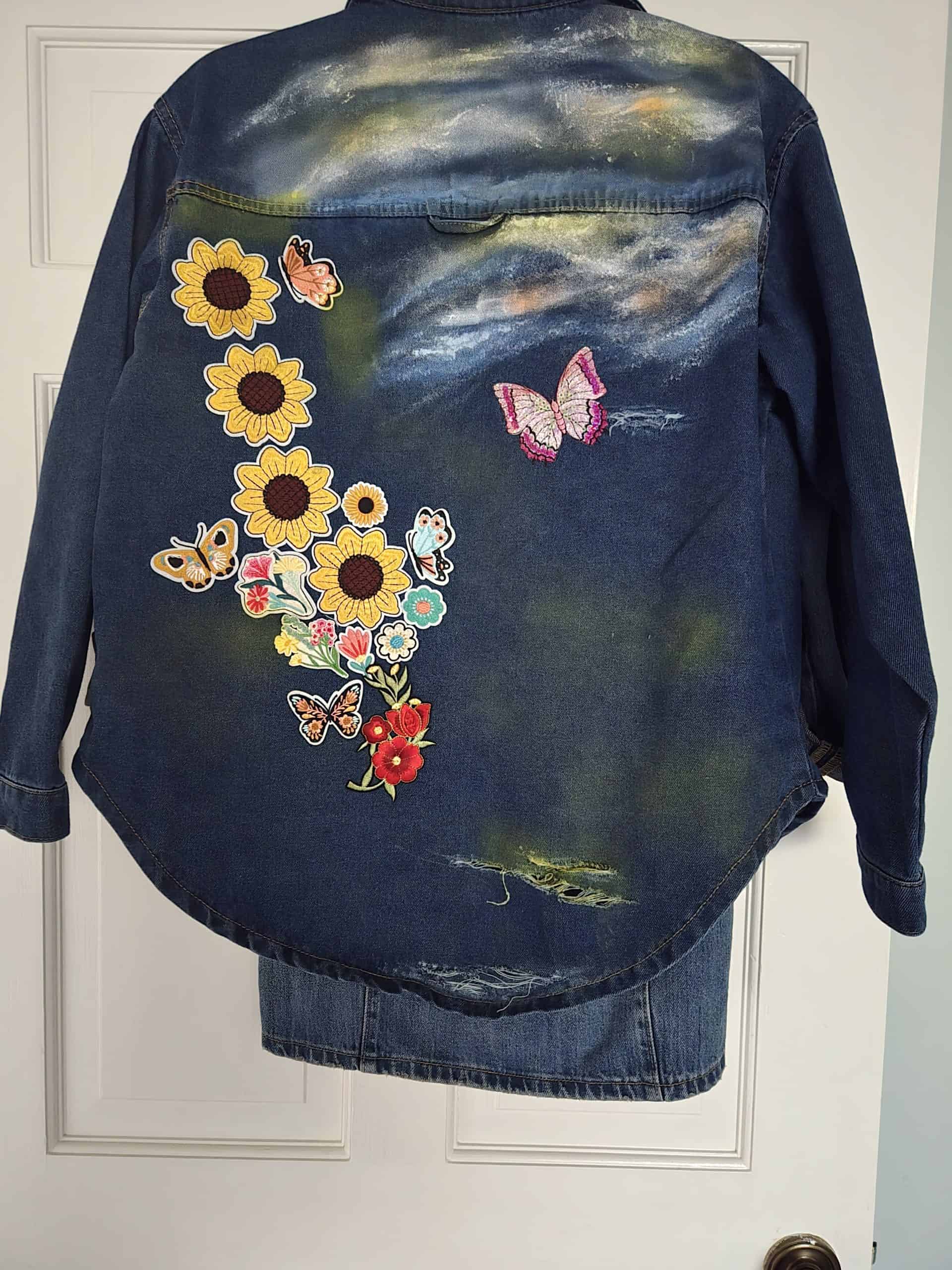 Embroidered sunflower and butterfly patches on a dark denim shirt, perfect for a stylish spring look.